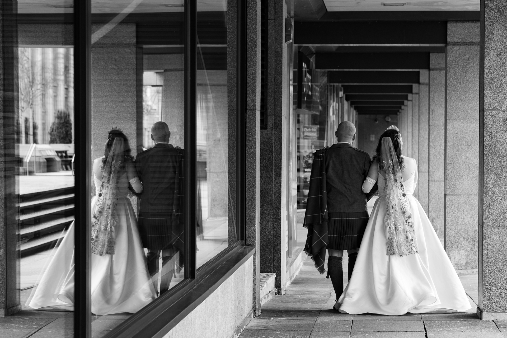Alternative Aberdeen Wedding Photography: Newlywed couple are reflected in windows as they walk through Aberdeen city centre.