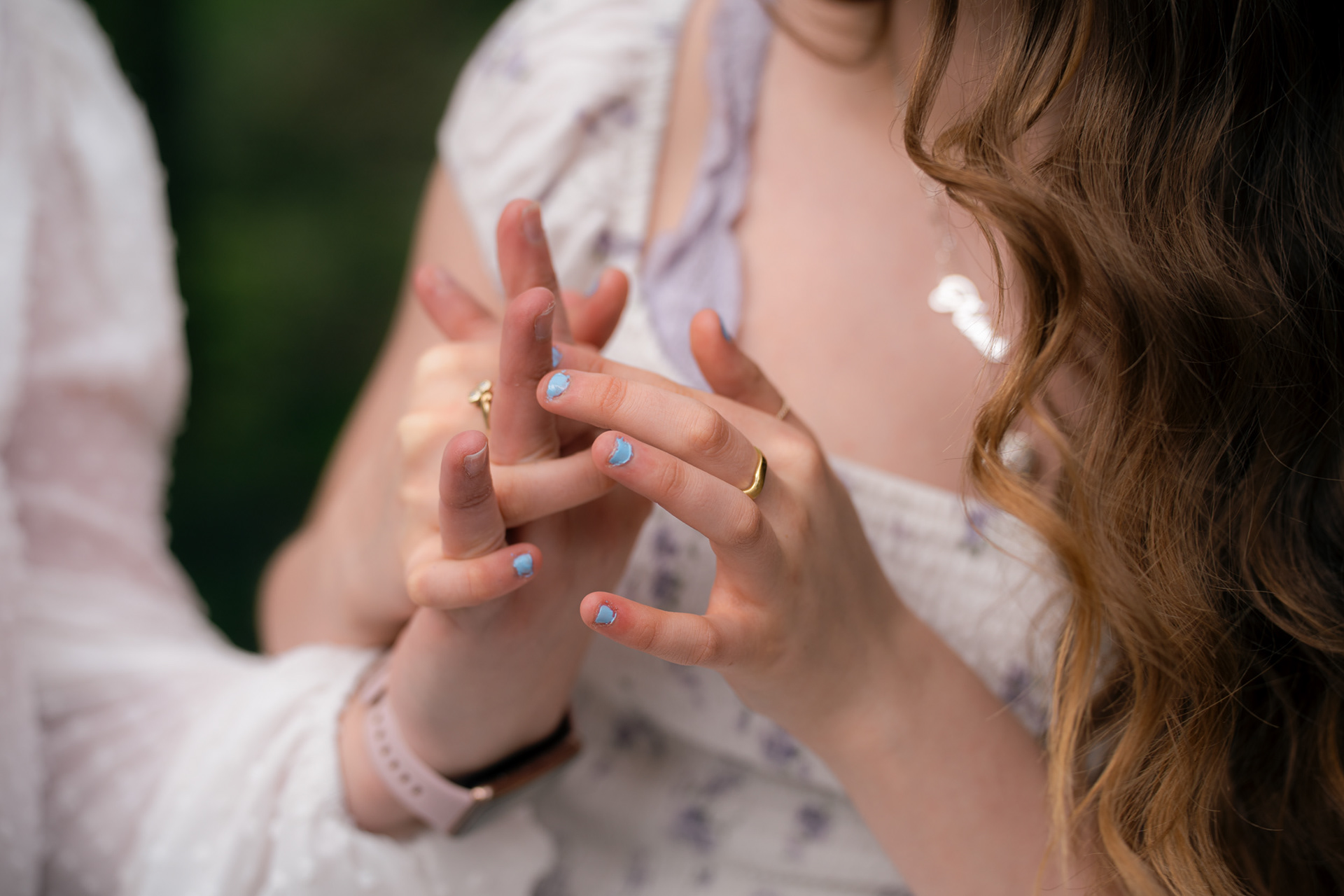 A mother and daughter's hands are pictured, fingers interlaced, at their Aberdeen family photo shoot. Both have white skin and are wearing a small number of gold rings. The daughter is wearing pale blue nail varnish.