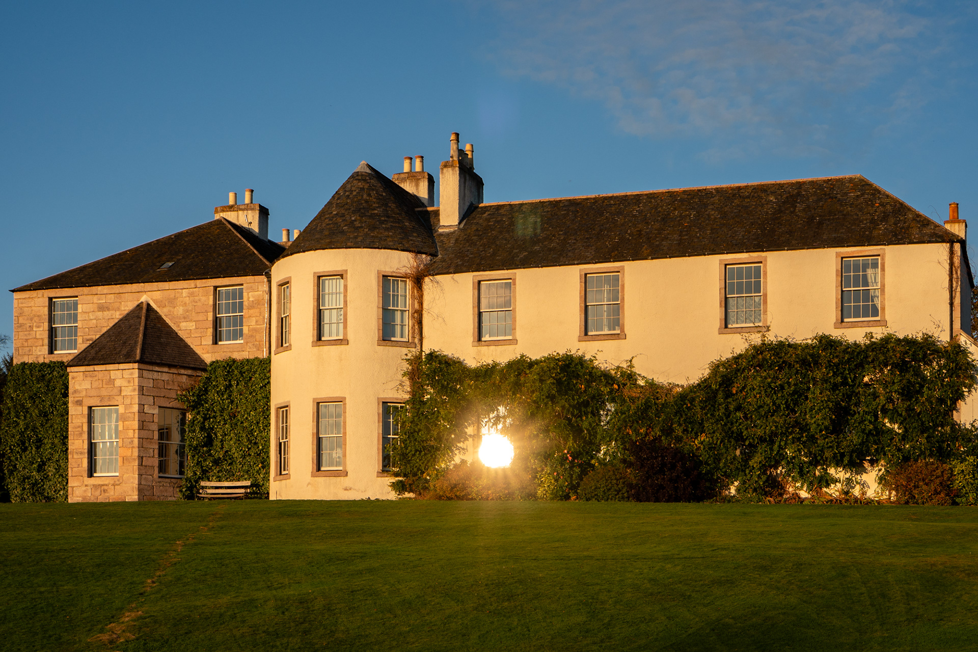 Logie Country House, an exclusive use wedding venue in Aberdeenshire, lit by autumn sunlight, with light bouncing off a ground floor window.