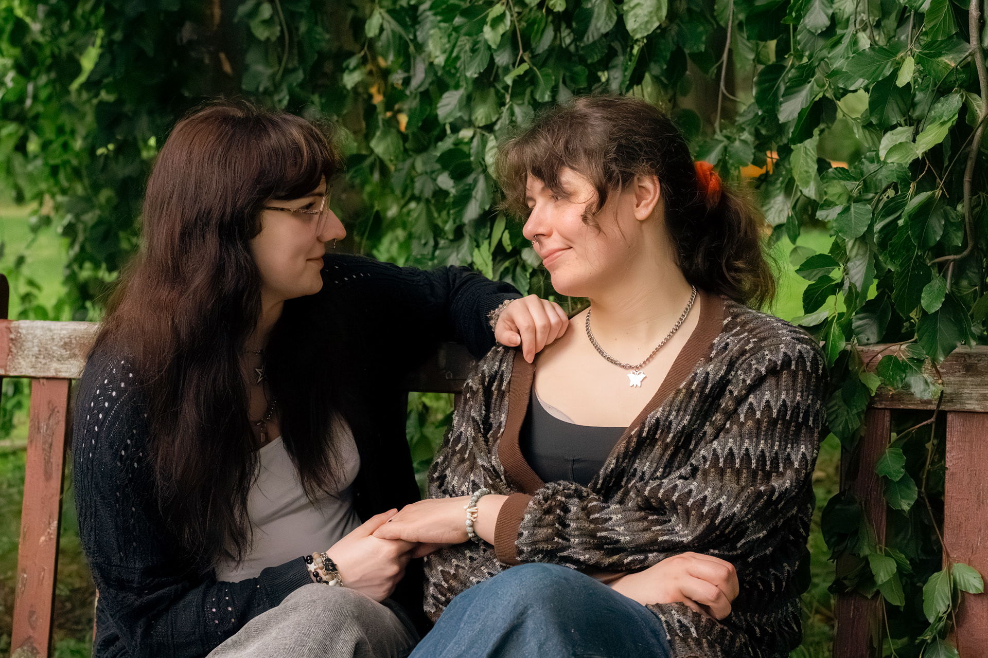 Aberdeen wedding photographer, Sarah, took this photo of two wives gazing at each other on a wooden bench. They are holding hands, and one wife has their hand resting on their partner's shoulder.