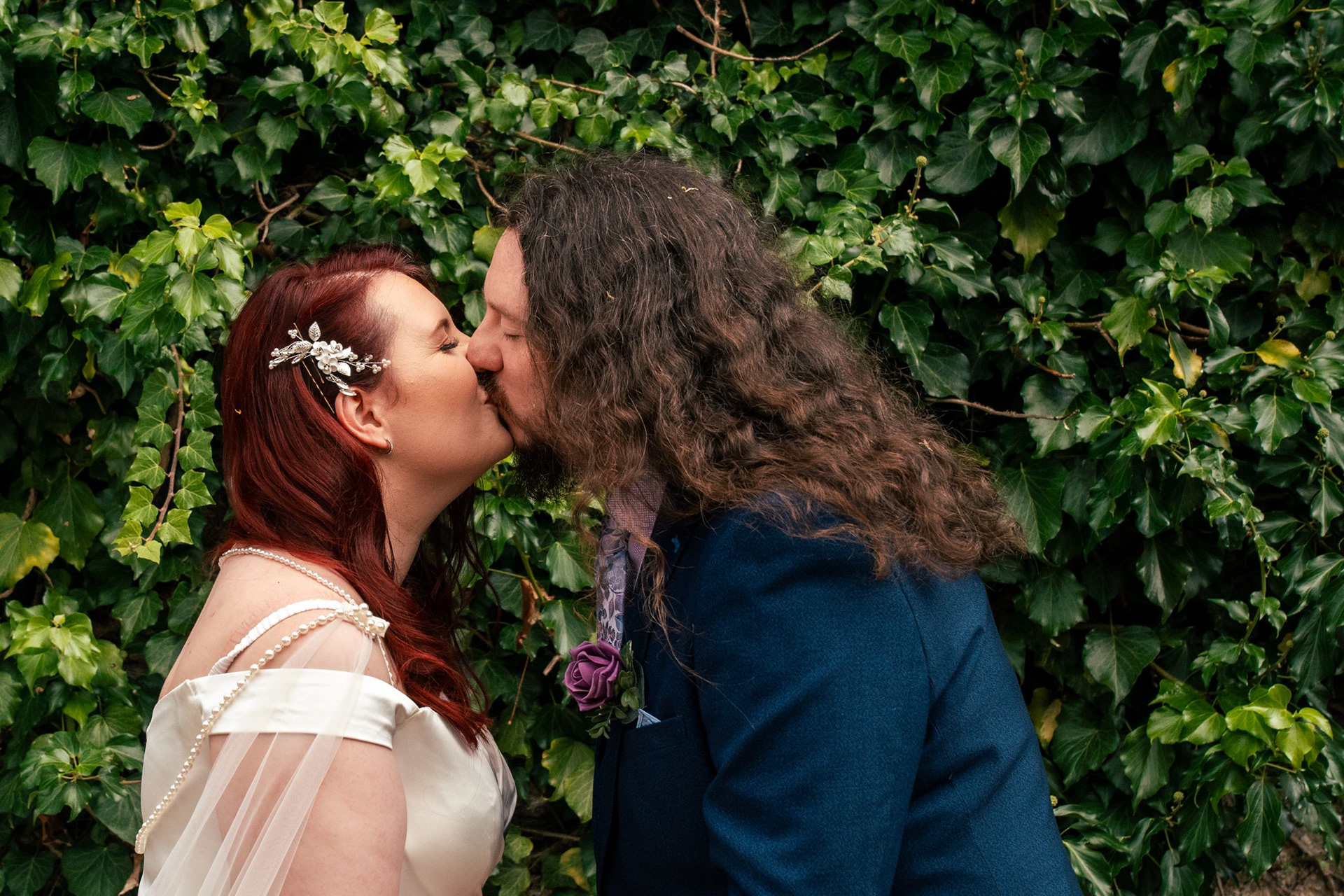 A newlywed couple kiss in front of a wall of ivy after their Aberdeen Winter Gardens wedding ceremony.