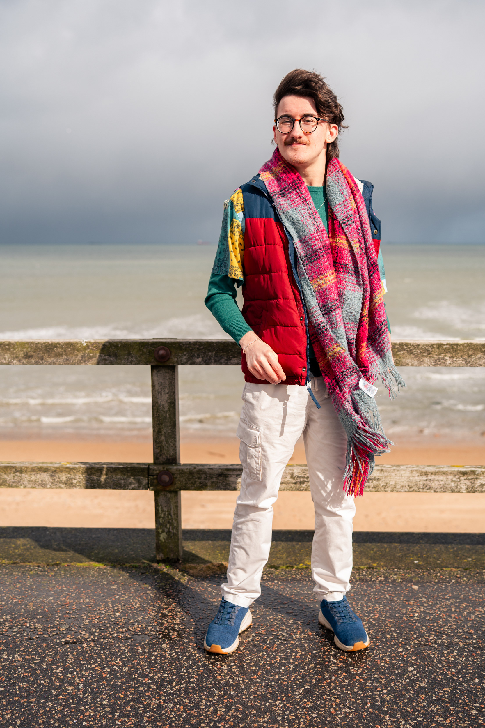 A white man in colourful clothes looks straight at the camera, with Aberdeen Beach as the backdrop.