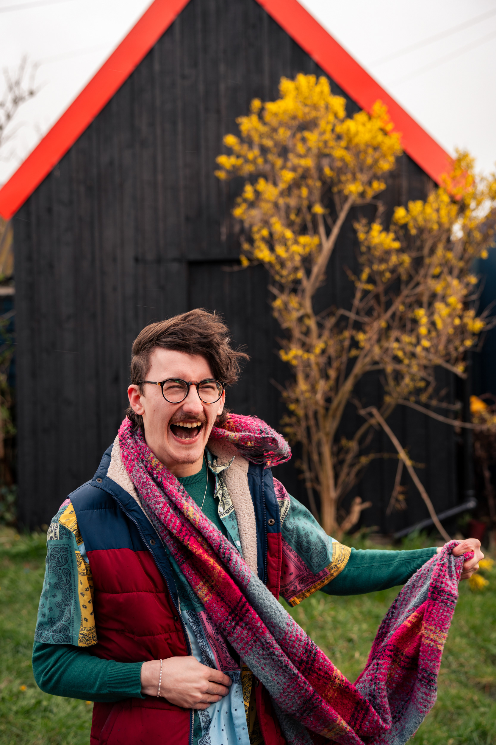 A young man laughs against a backdrop of a Fittie hut.