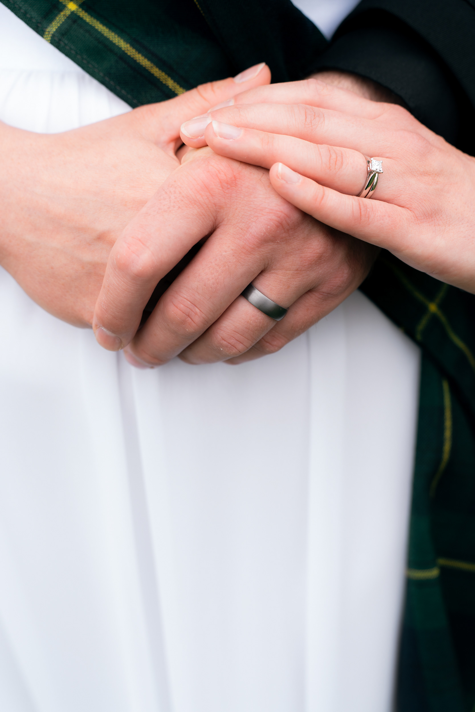 Alternative Aberdeen wedding photographer: Close up of bride and groom's hands, loosely clasped, with new wedding rings pictured.