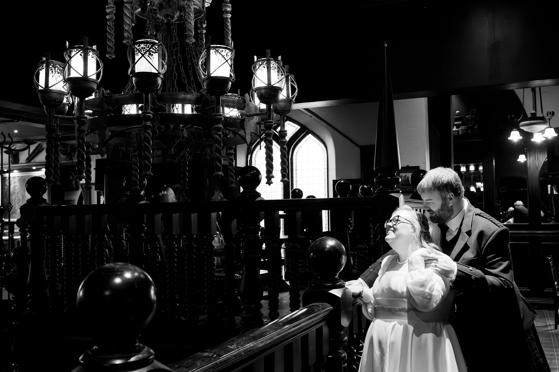 Alternative Aberdeen wedding photography: Black and white photo of bride and groom laughing on a balcony in Slains Castle pub.