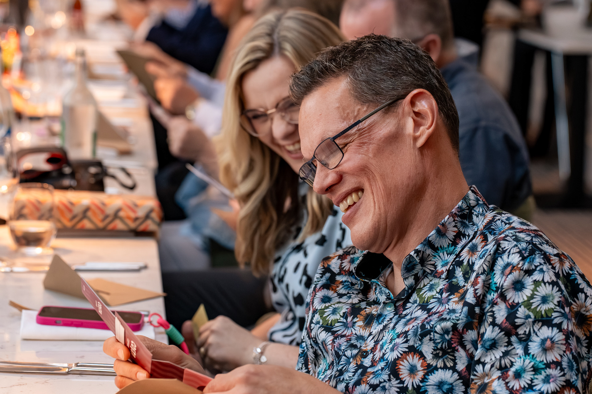 Aberdeen Photographer: A blonde woman and dark-haired man in floral shirt laugh hard as they look at a Costa gift voucher.