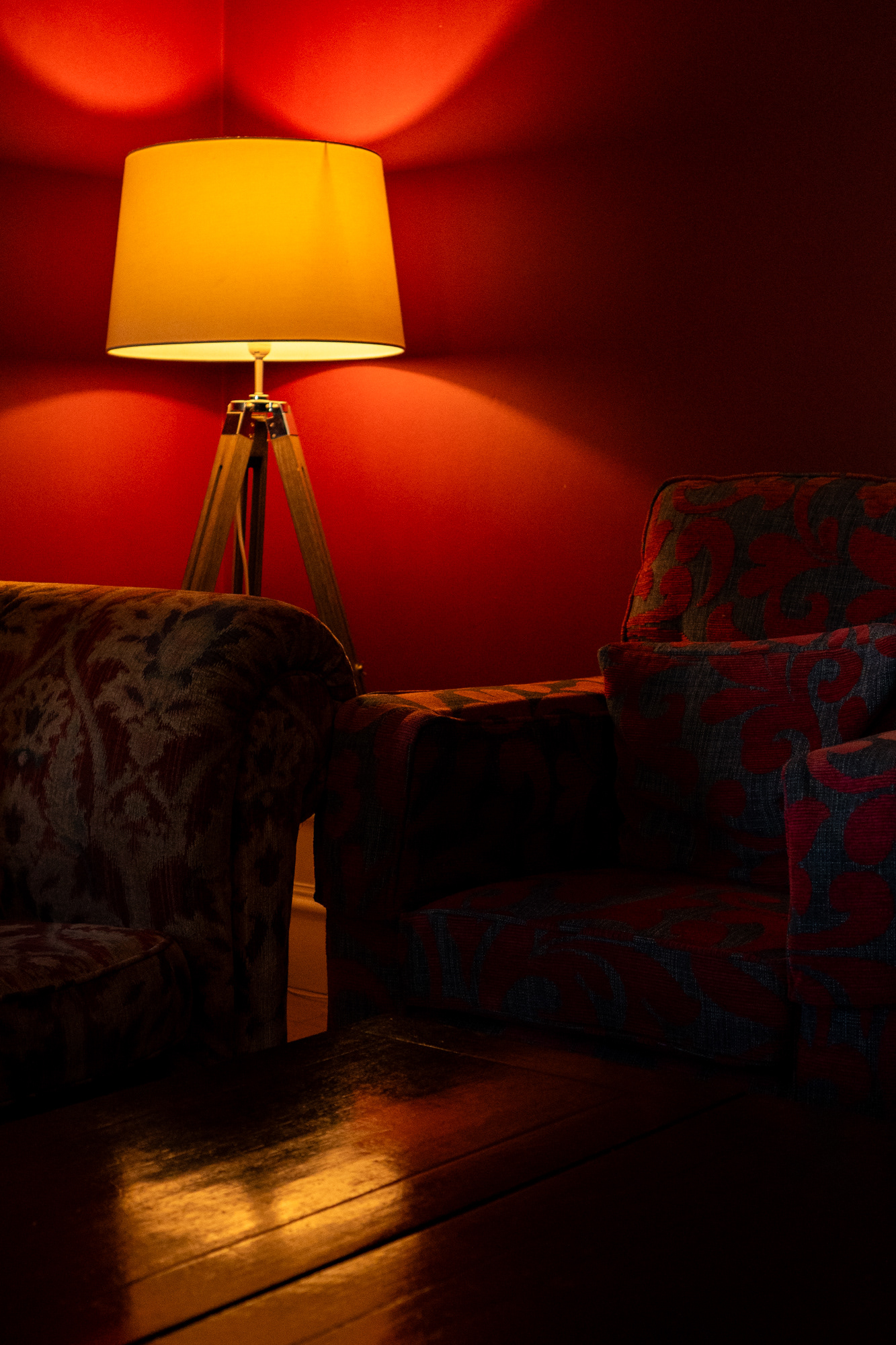 Logie Country House: A lamp in a corner throws yellow light over red walls and armchairs