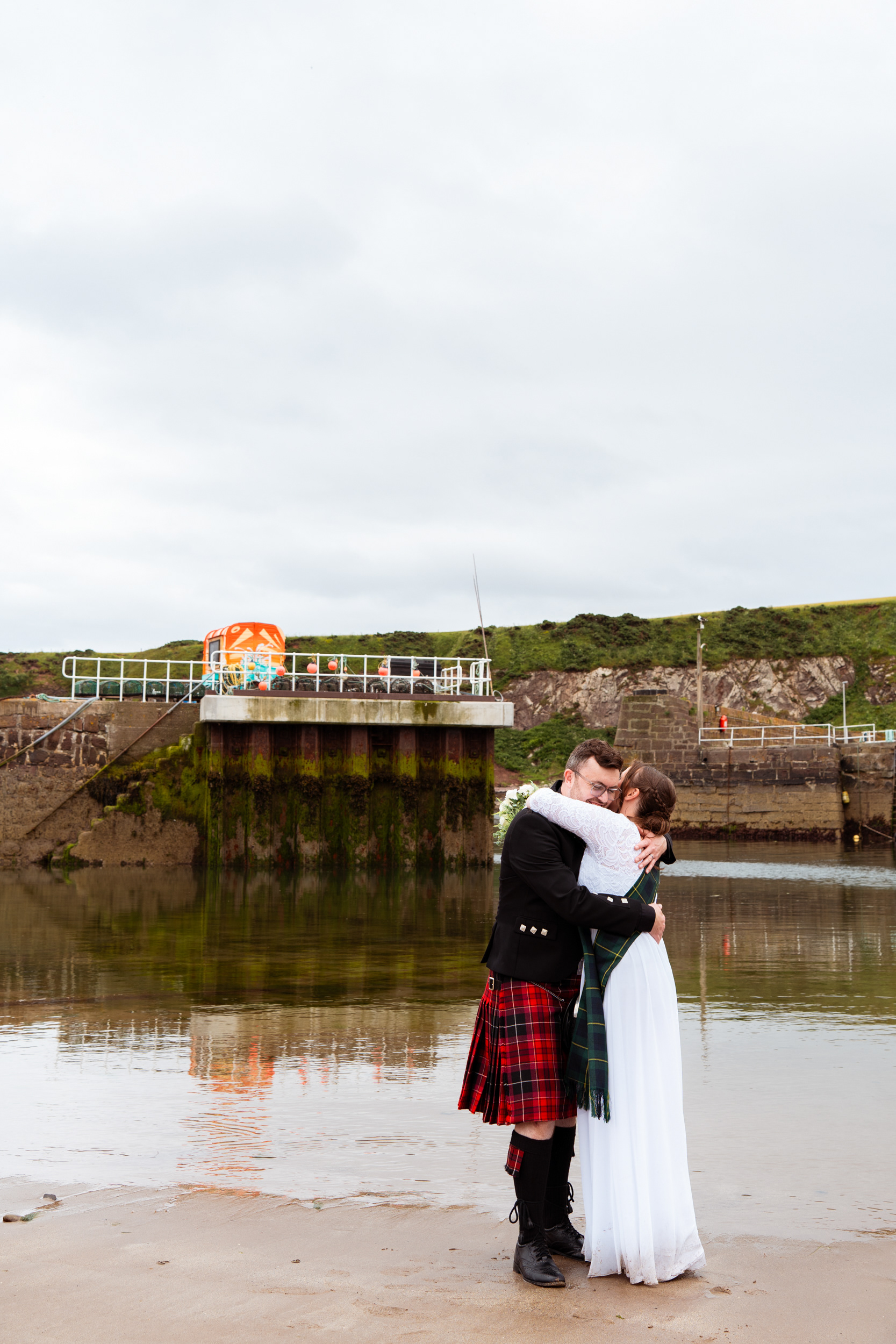Stonehaven elopement: Bride and groom hug by the water at the harbour.