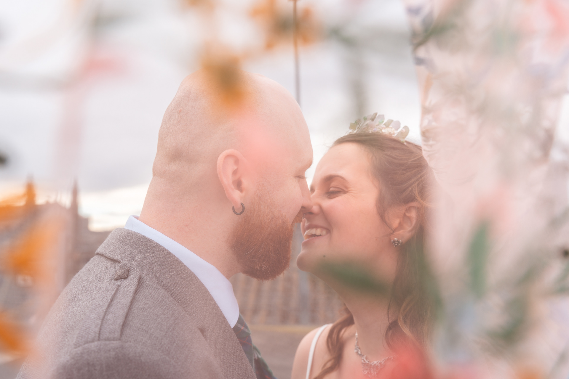 Bride and groom, partially obscured by a floral veil, kiss on an Aberdeen City rooftop.
