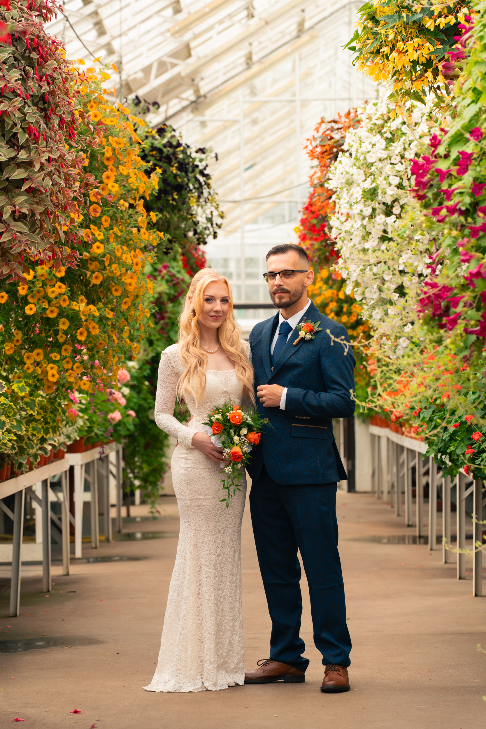 Duthie Park Winter Gardens wedding: Bride and groom surrounded by colourful flowers in the Victorian Corridor.