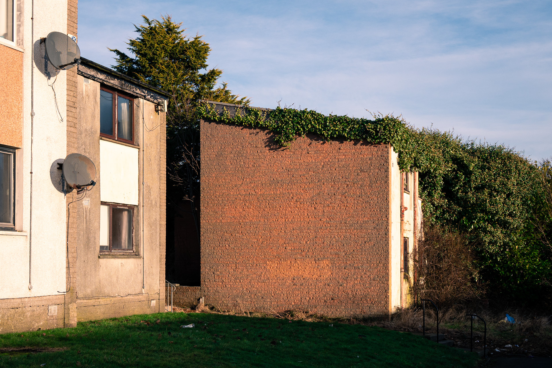 Empty houses in the sunshine. Ivy has grown up and over one long-abandoned building.
