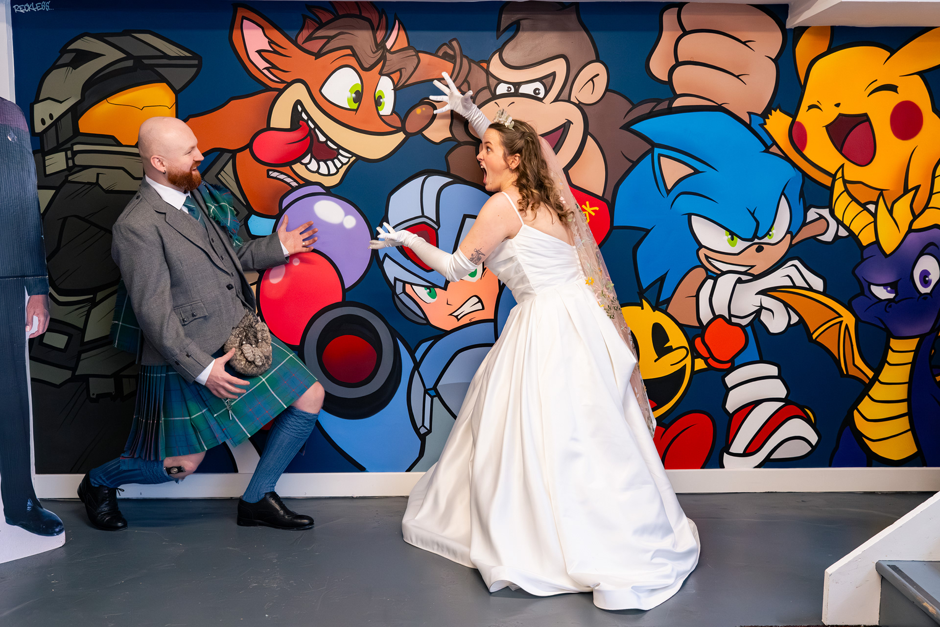 Alternative Aberdeen Wedding Photography: Newlyweds pull silly poses in front of a mural in Video Games Aberdeen.