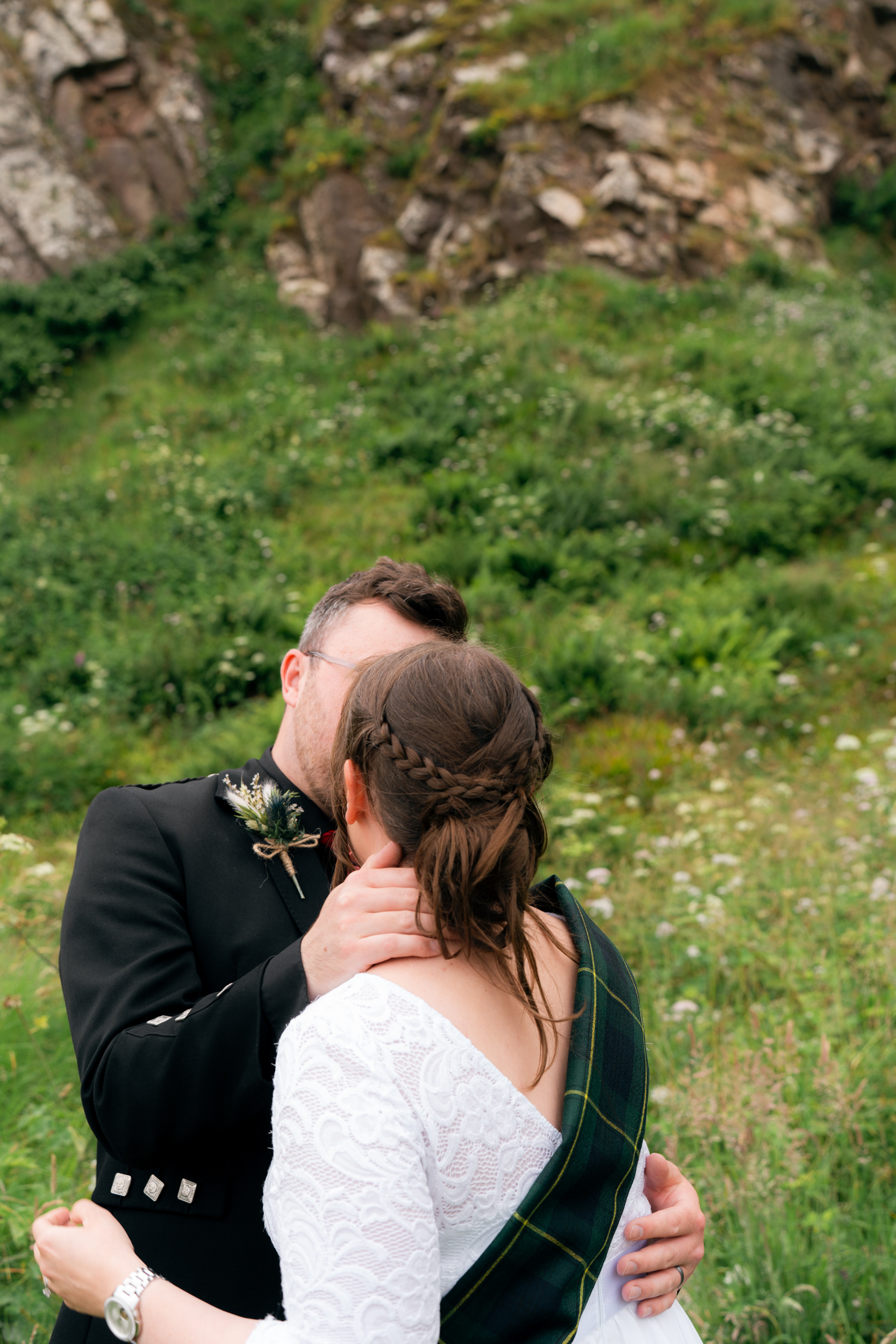 Stonehaven wedding photography: Bride and groom kiss against a backdrop of wildflowers.