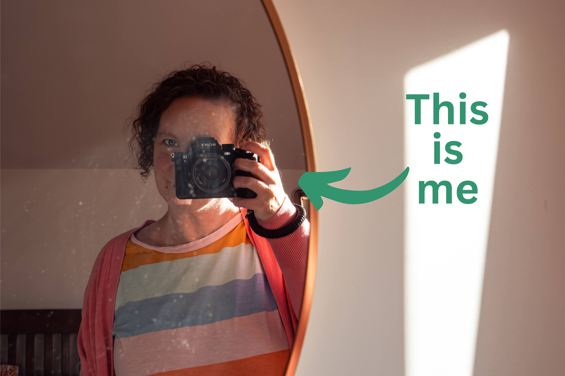 Aberdeen wedding photographer, Sarah from Windswept Stories, taking a selfie in a mirror. She has short curly hair and wears a pastel stripy T-shirt. Overlaid is the text "This is me".
