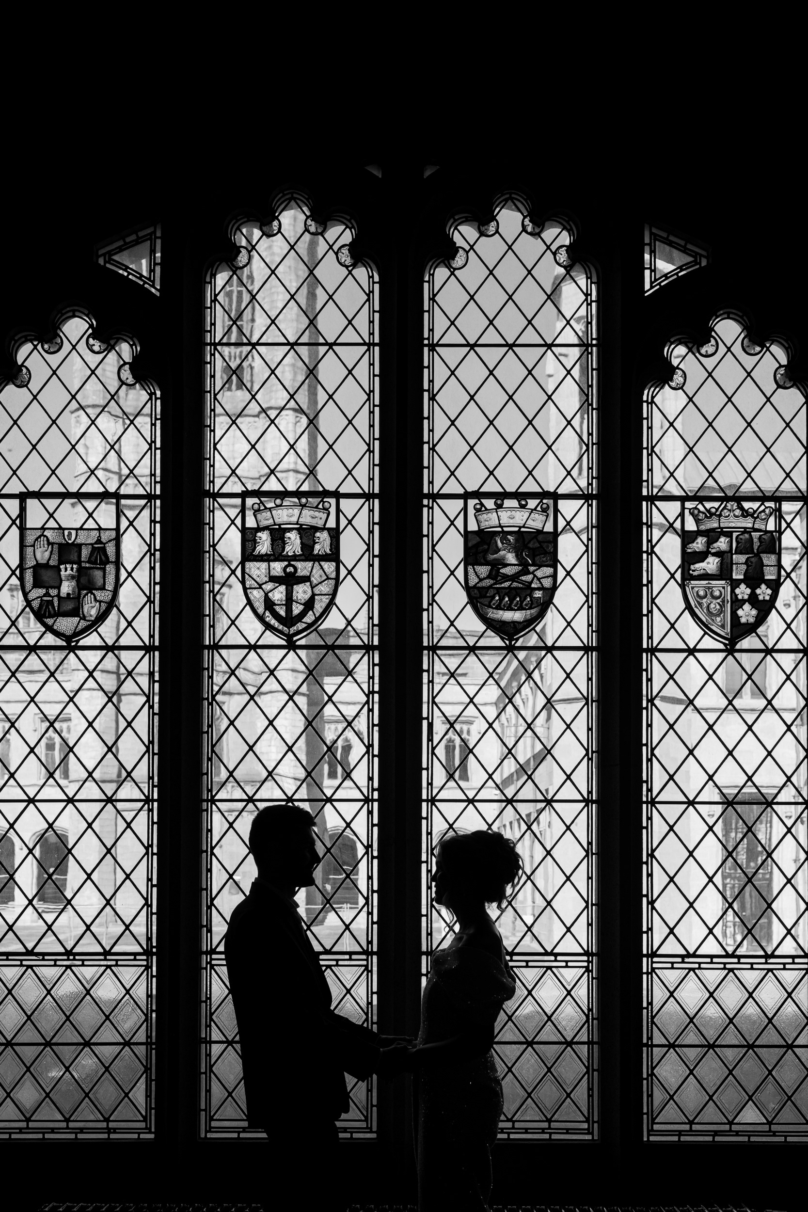 Black and white photo of a couple silhouetted against a stained glass window in Aberdeen's registry office at Marischal College.