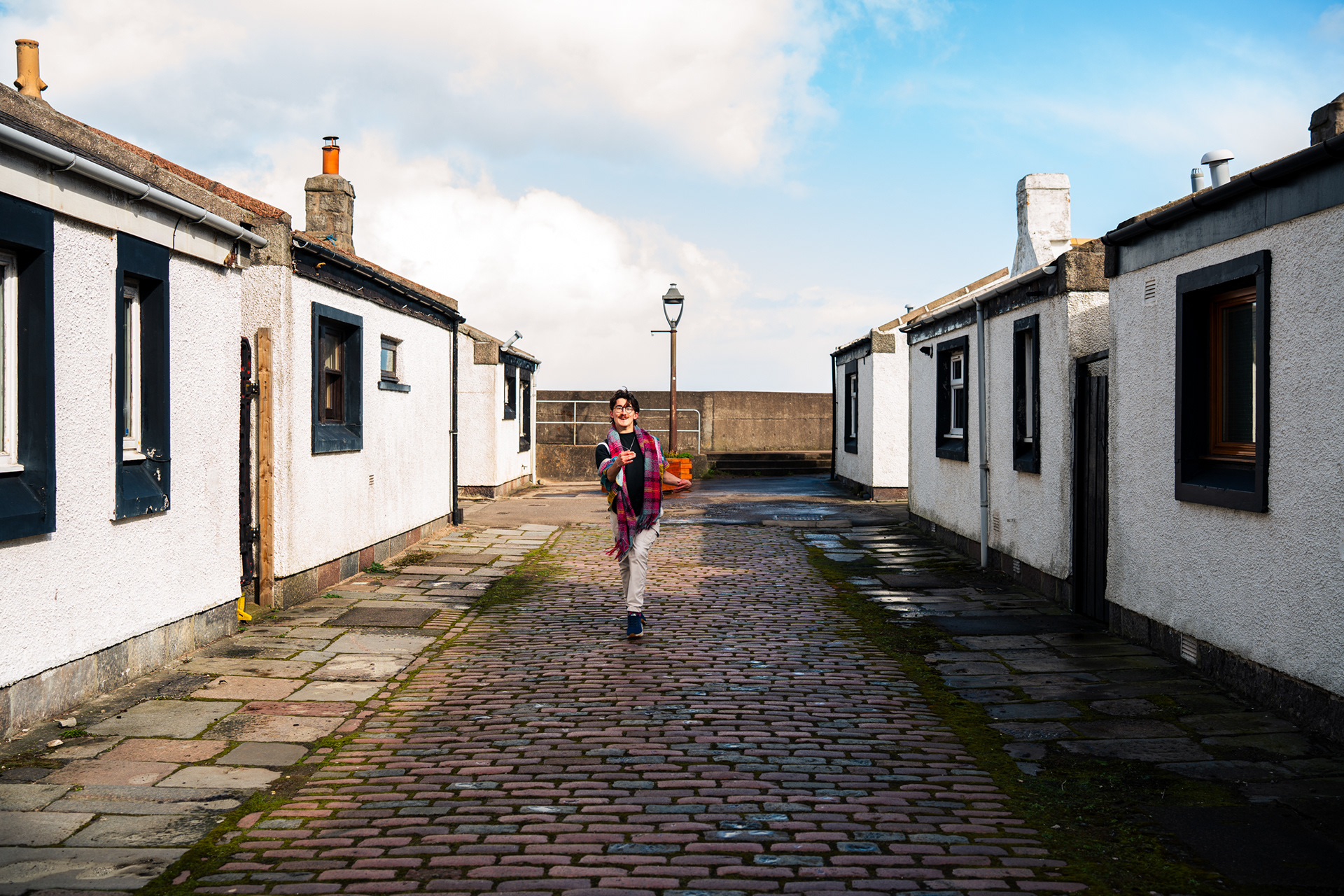 A man with cerebral palsy struts towards the camera down a cobbled street in Aberdeen.