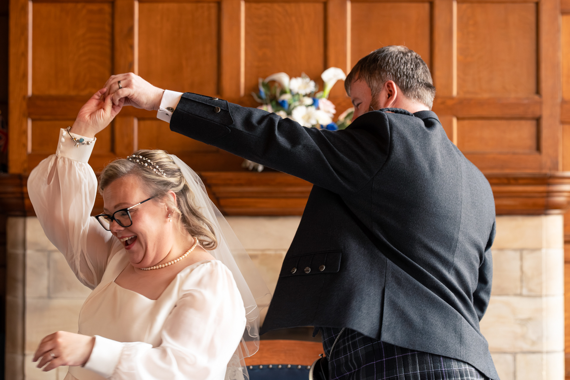 Aberdeen wedding photography: Bride in white twirls under her groom's arm during their Marischal College wedding ceremony.