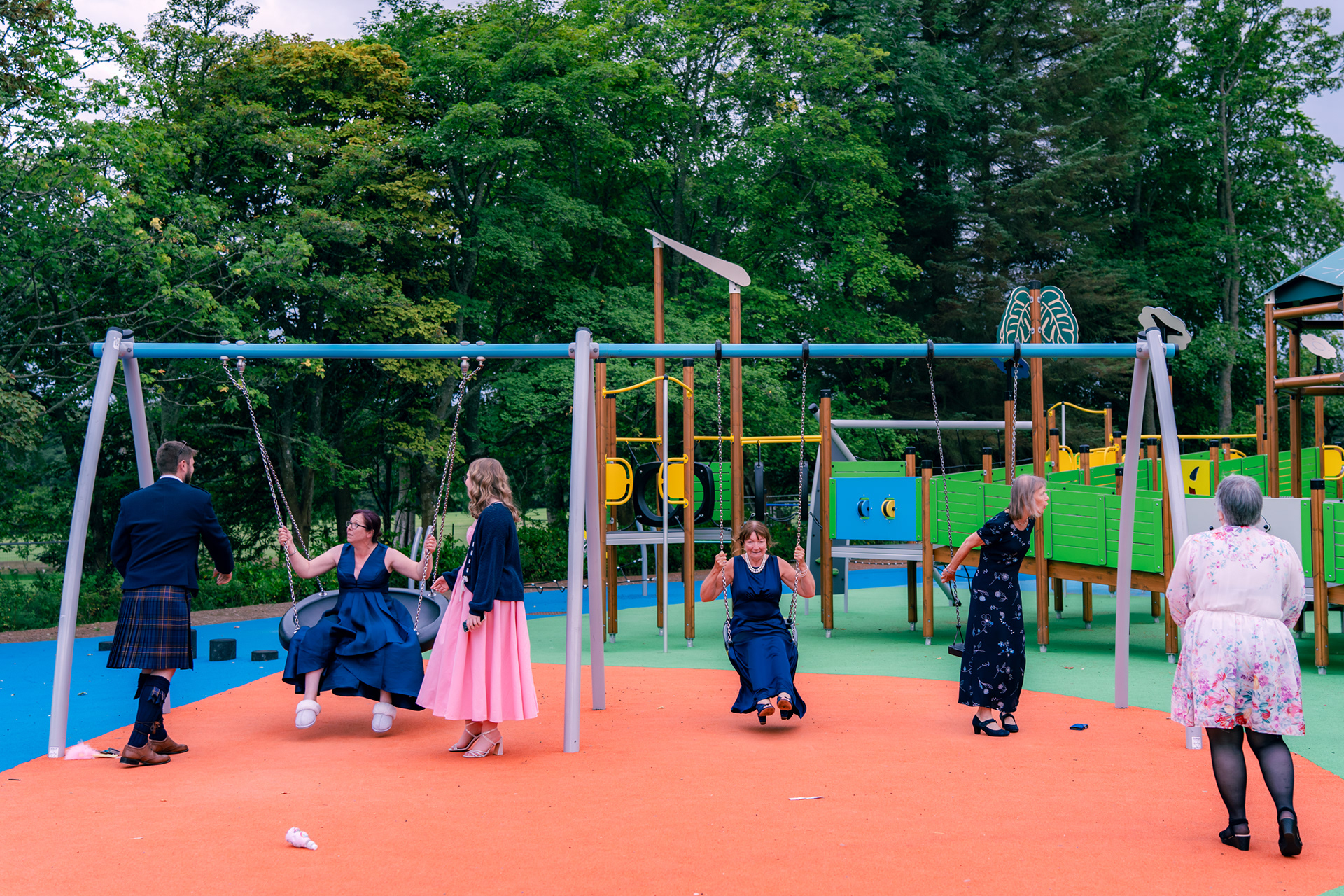 Wedding guests in Aberdeen play on the swings