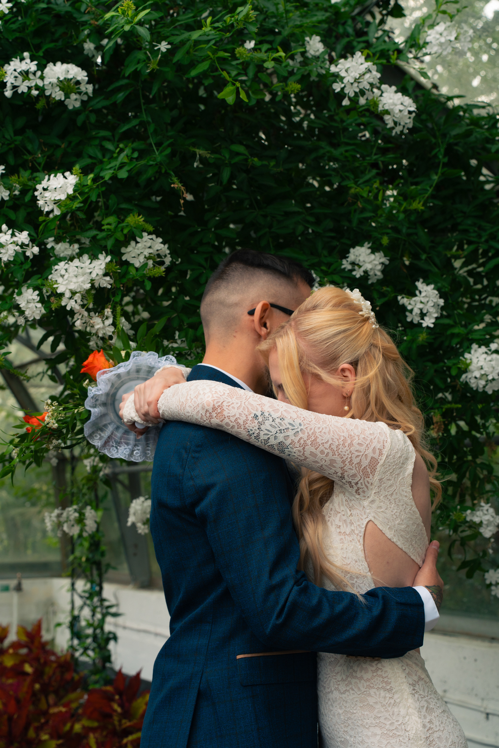 Duthie Park Winter Gardens wedding: Bride and groom hug in front of an arch of white flowers.