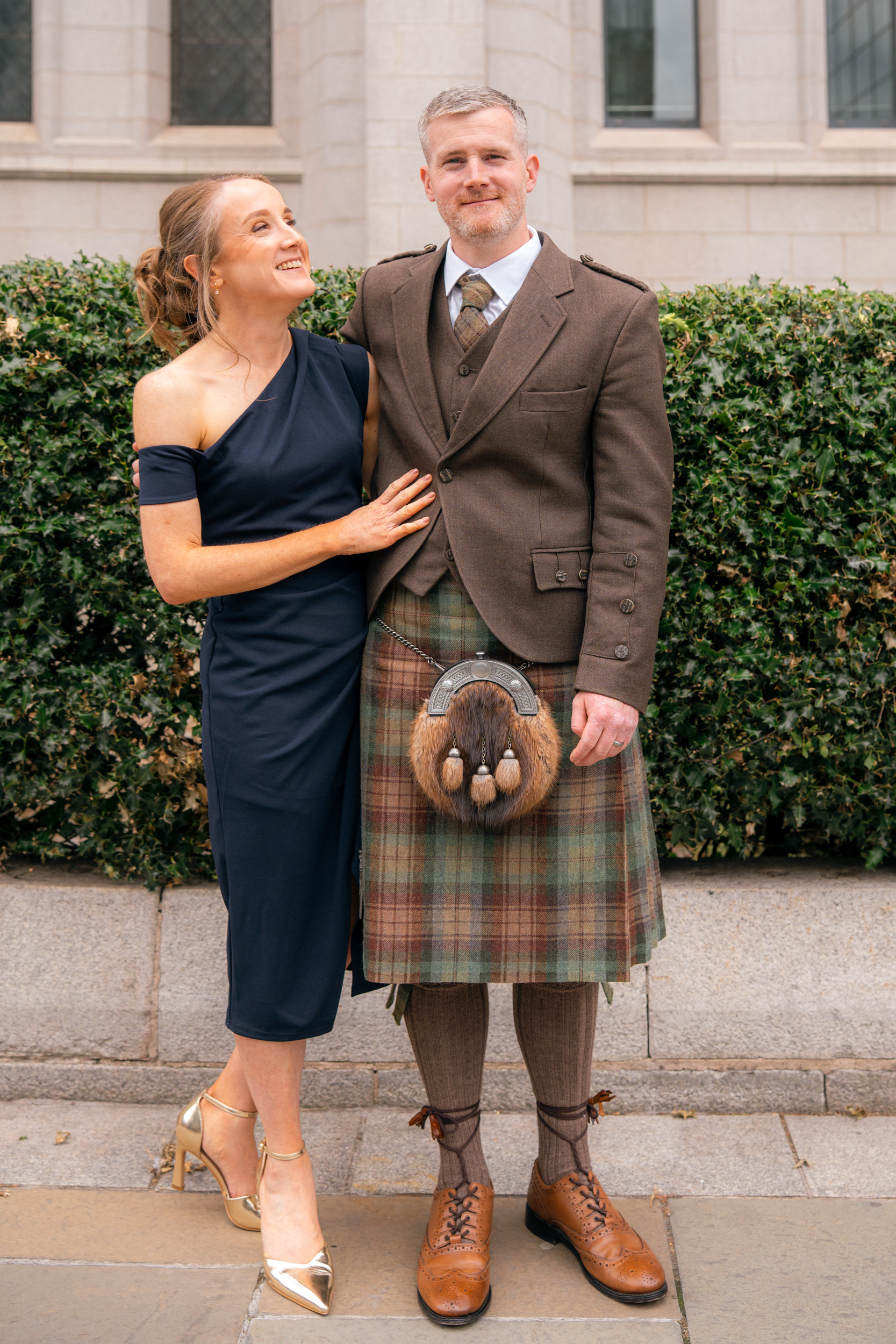 Marischal College wedding: Groom in brown kilt hugs his sister in navy dress.