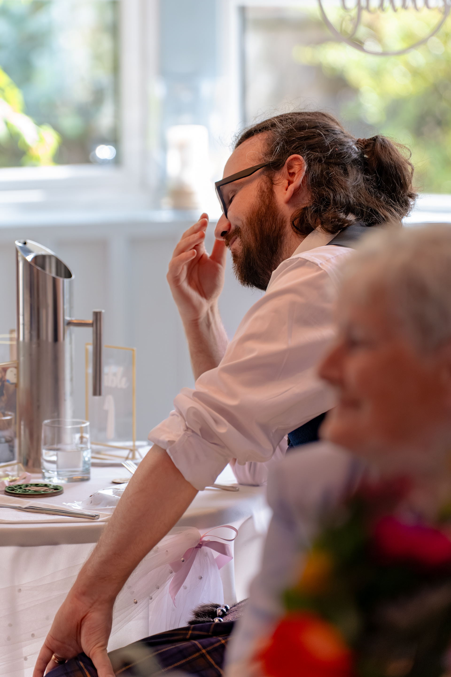 A groom puts his head in his hands during his brother's speech