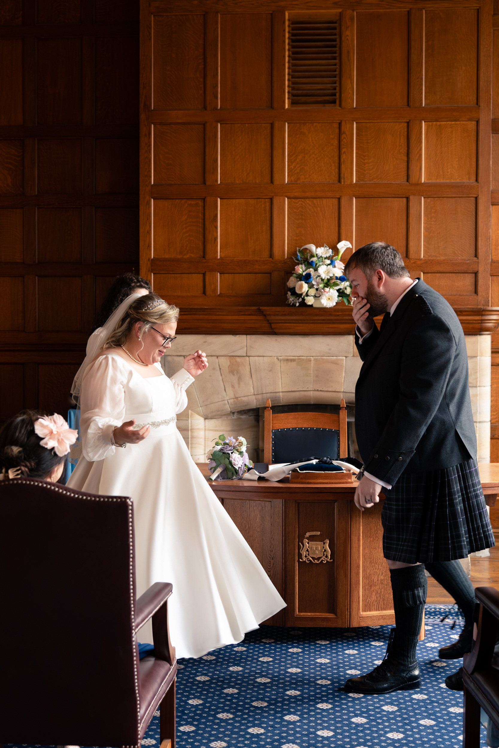 Bride dances during Marischal College wedding while groom looks on in awe.