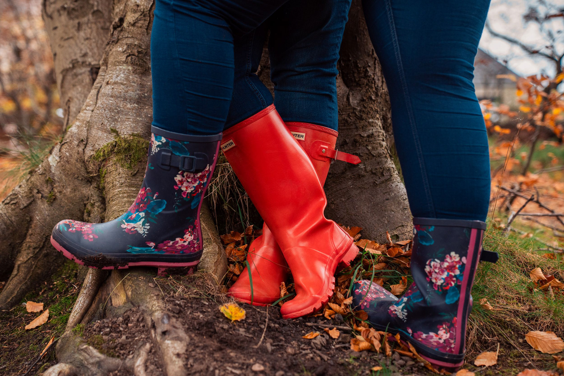 Red Hunter wellies and floral navy wellies, at the ends of legs wearing jeans, positioned so it's obvious the wearers are kissing against a tree. Taken during an Aberdeen pre-wedding photo shoot.