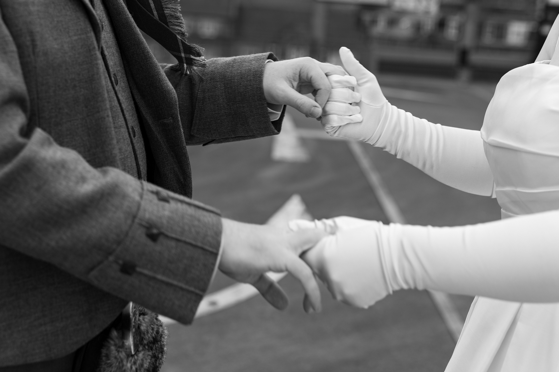 Close up of bride and groom's hands, holding each other. She is wearing full length white gloves.