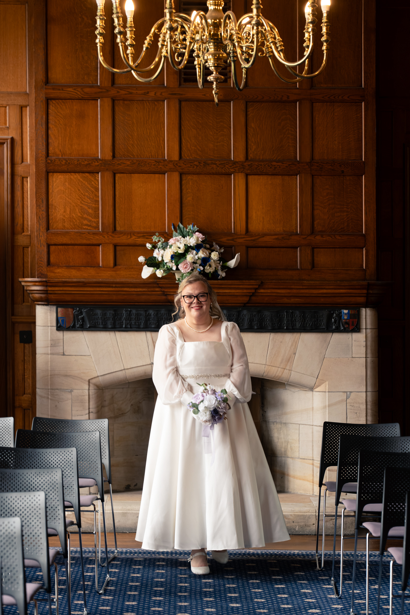 Beautiful bride in white dress walks down the aisle at Marischal College.