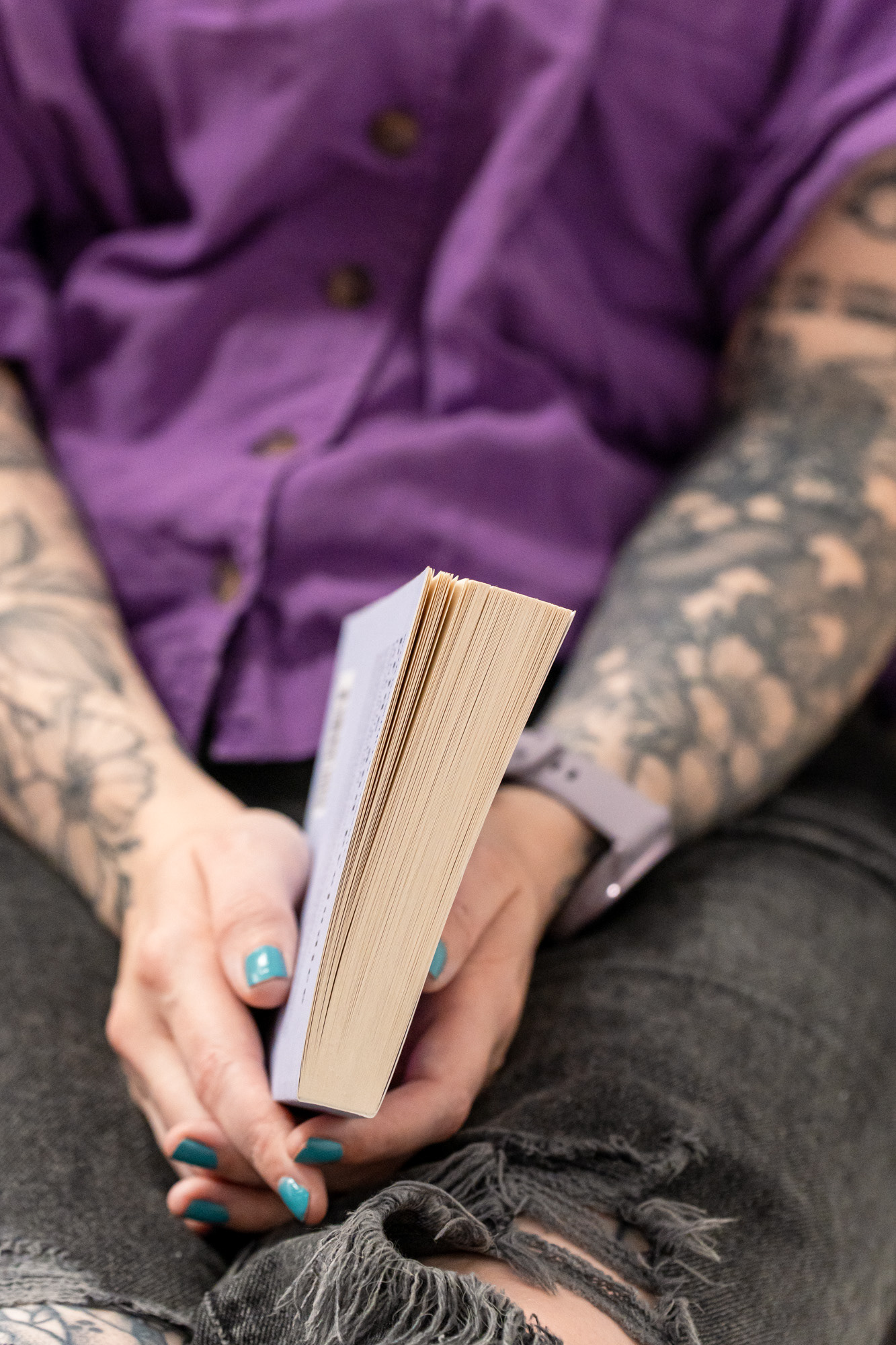 Aberdeen branding photography: detail shot of white hands with teal nails loosely holding a paperback book.