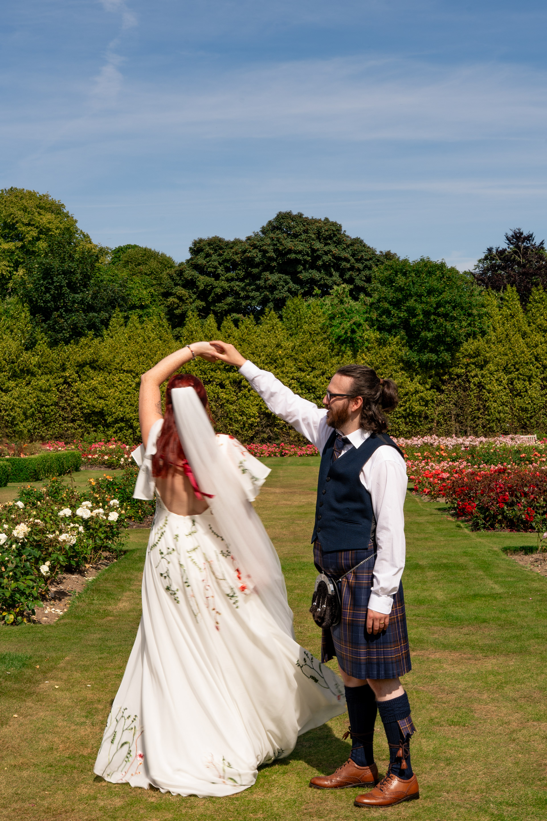 A bride twirls under groom's arm, her dress and veil a blur of movement