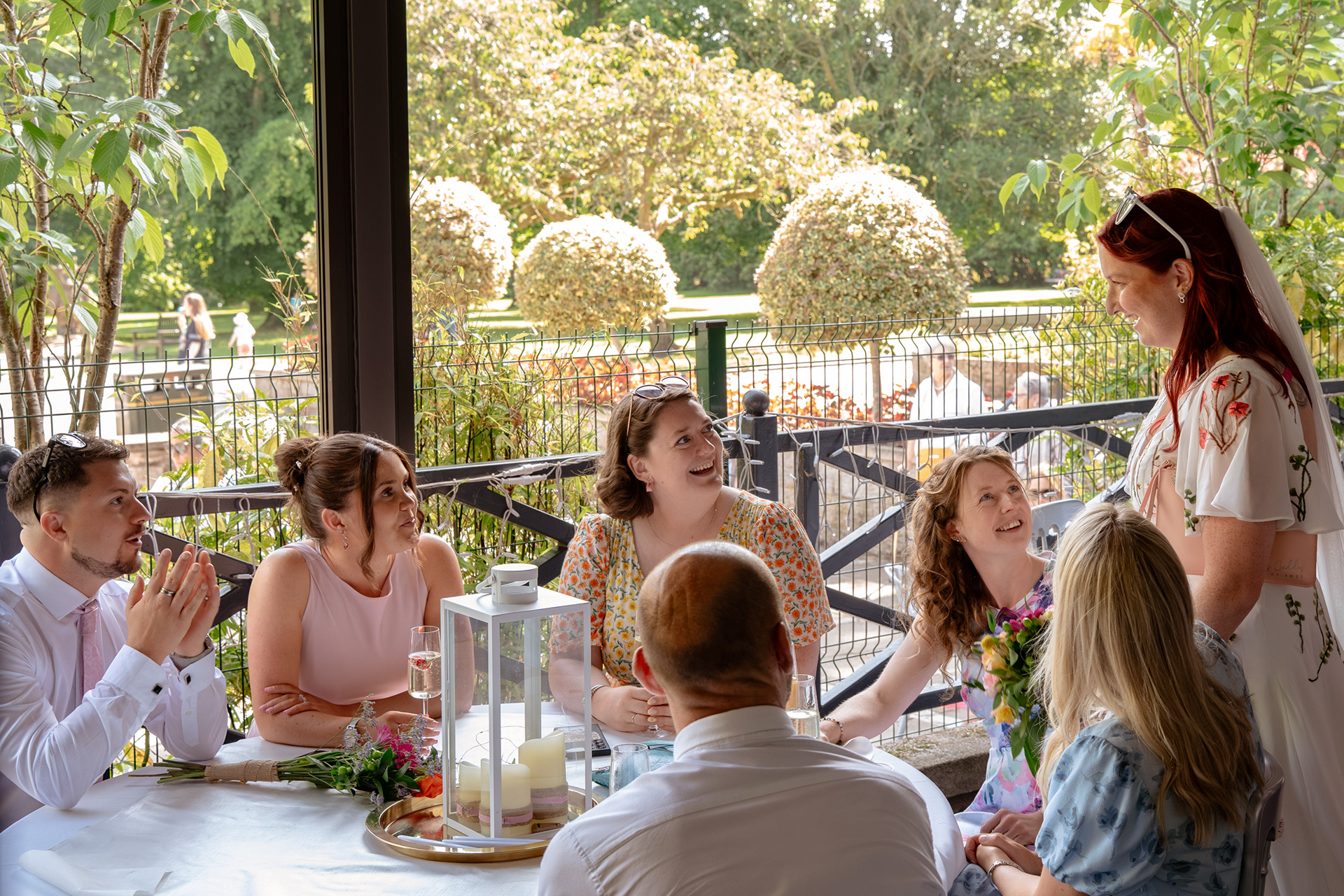 Guests seated around a table turn and smile at a bride