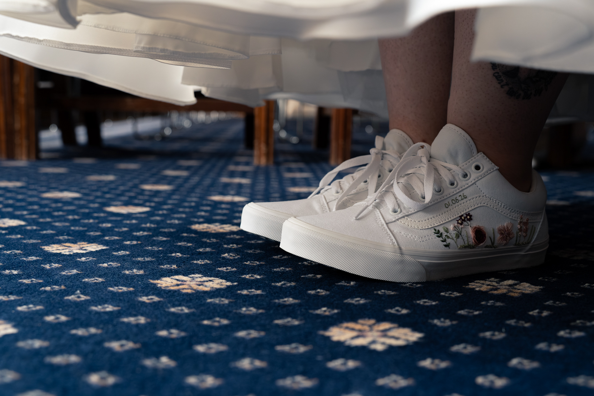 Alternative Aberdeen wedding photography: Personalised, embroidered white Converse peek out under bride's white dress.
