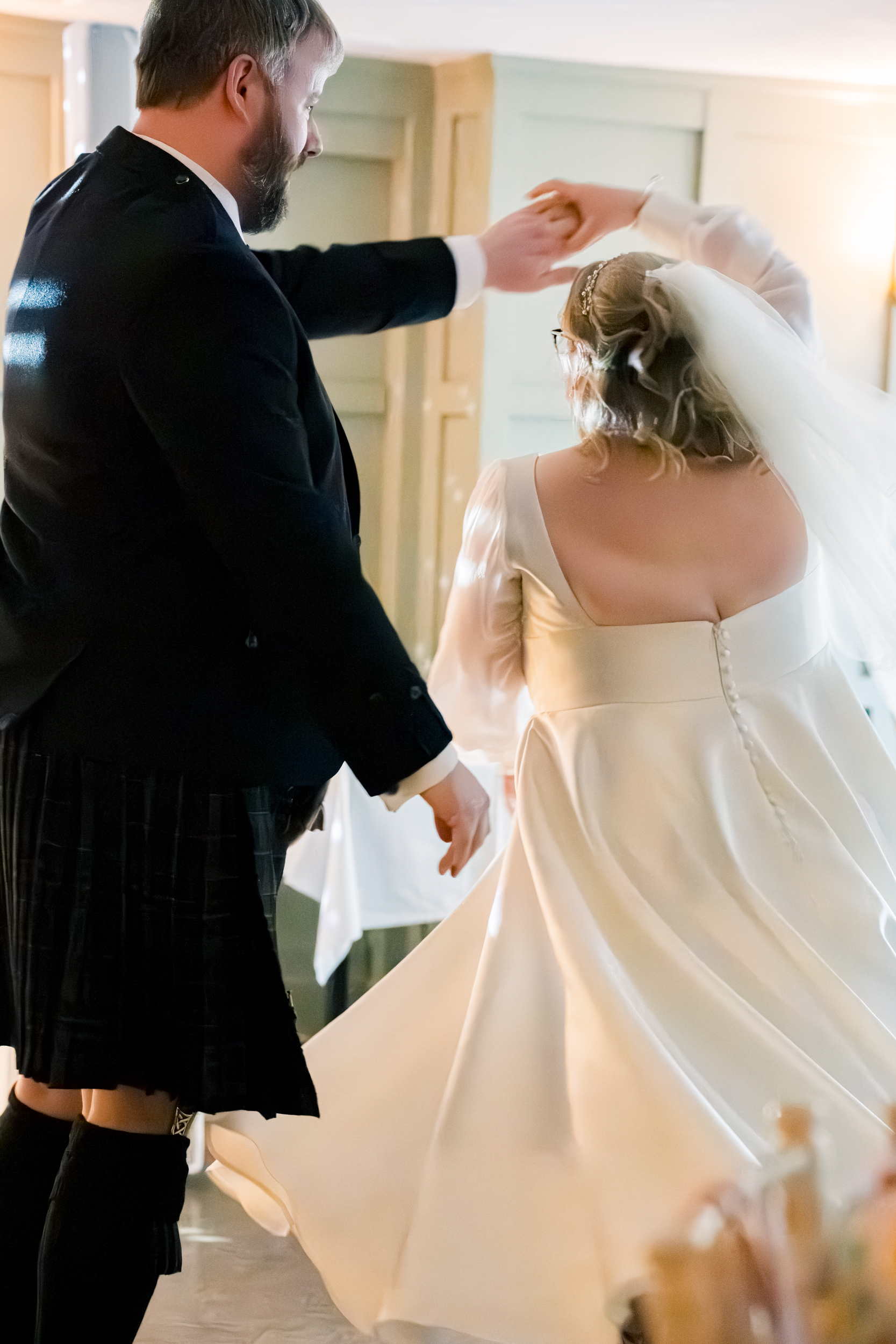 Aberdeen Palm Court Wedding: Bride twirls under groom's arm during first dance.