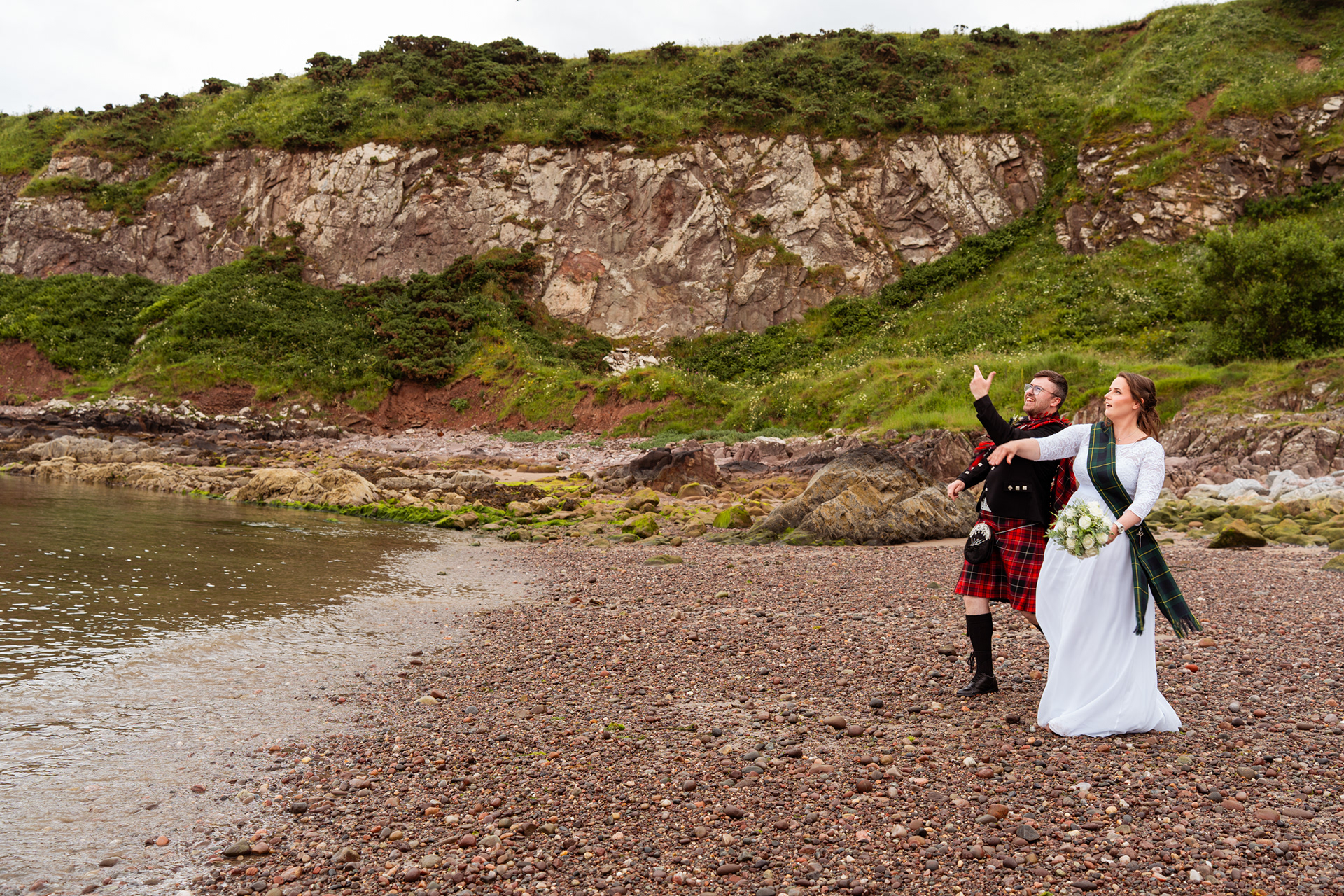 Alternative Stonehaven wedding photography: Bride and groom are seen skimming stones into the harbour.