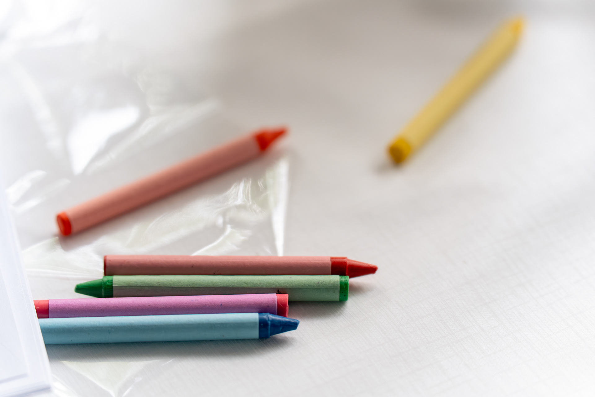 Colourful crayons scattered across a white tablecloth.