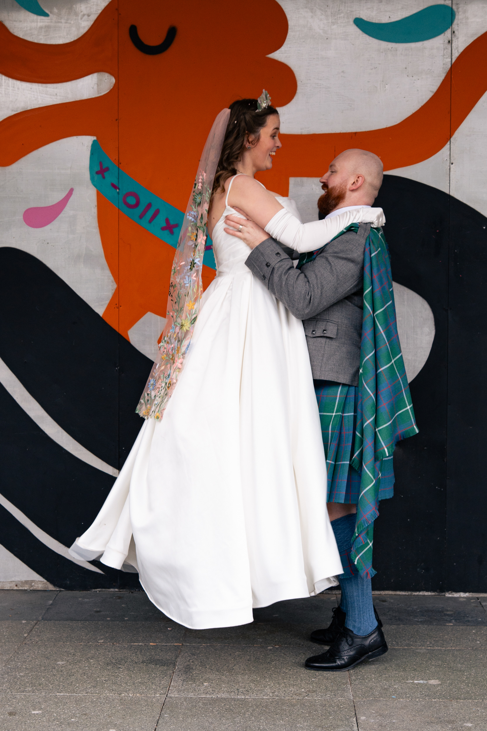 Alternative Aberdeen Wedding Photography: Bride and groom both look surprised and delighted as he lifts her into the air.