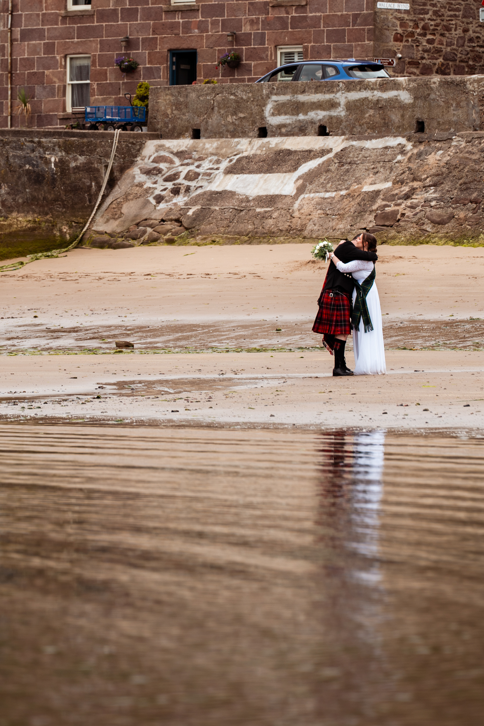Stonehaven elopement: Bride and groom hug by the water at the harbour.
