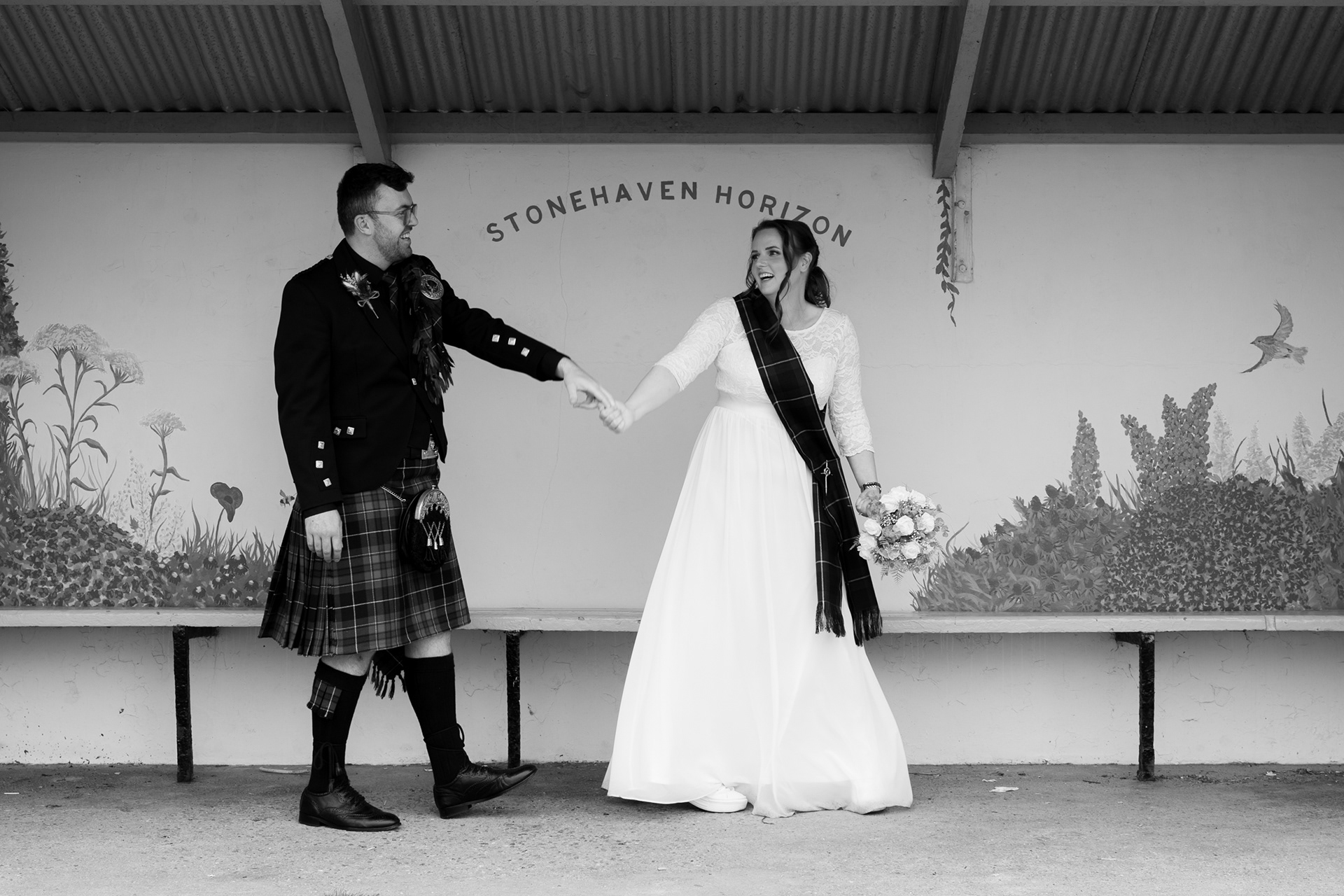 Aberdeenshire wedding photography: black and white photo of a bride and groom dancing in the Stonehaven Horizon shelter at the harbour.