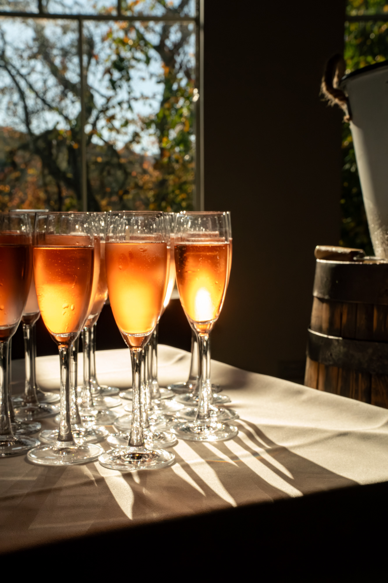 The sun shines through glasses of amber drinks at a wedding reception