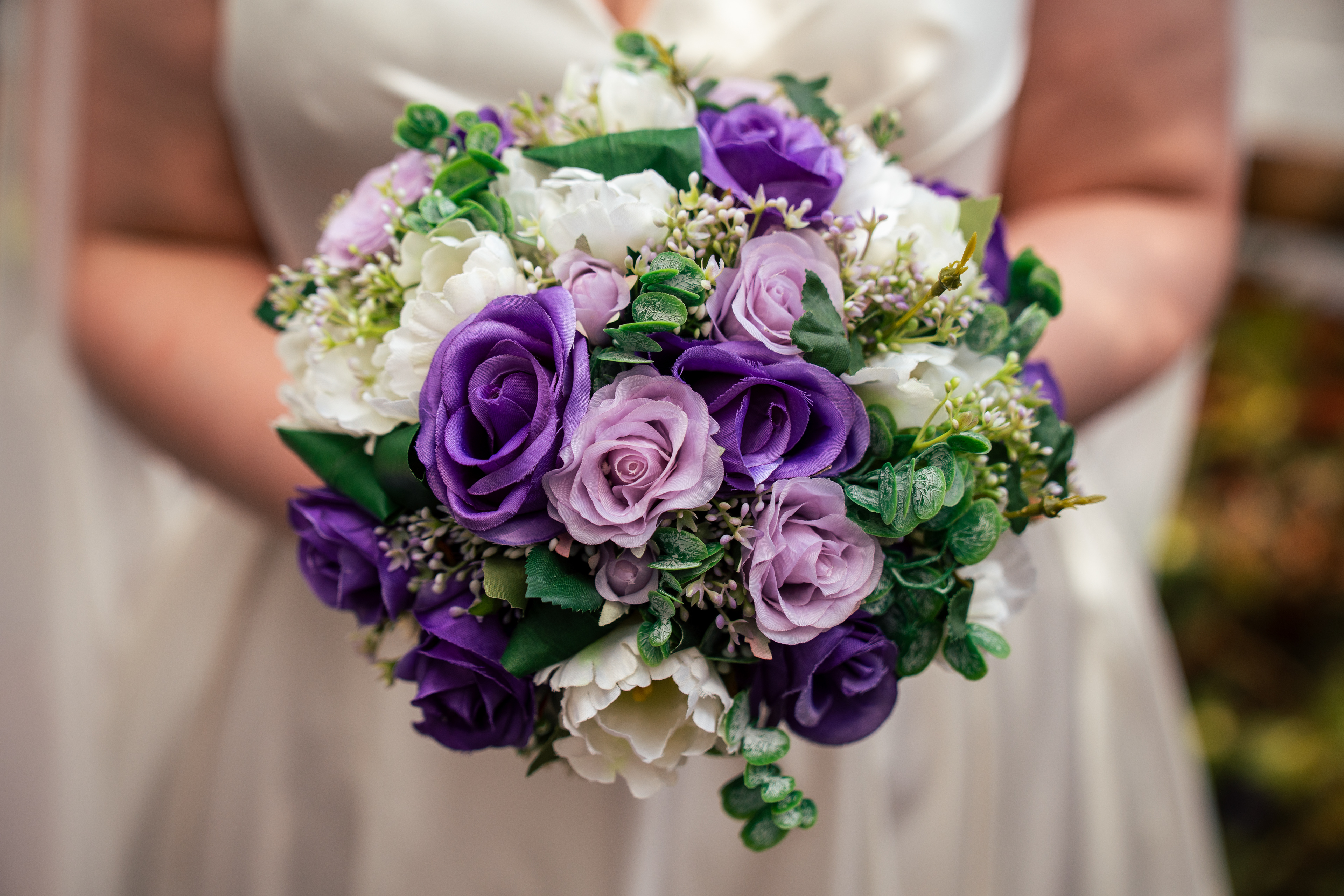 Detail shot of Mel's bouquet of purple and white roses.
