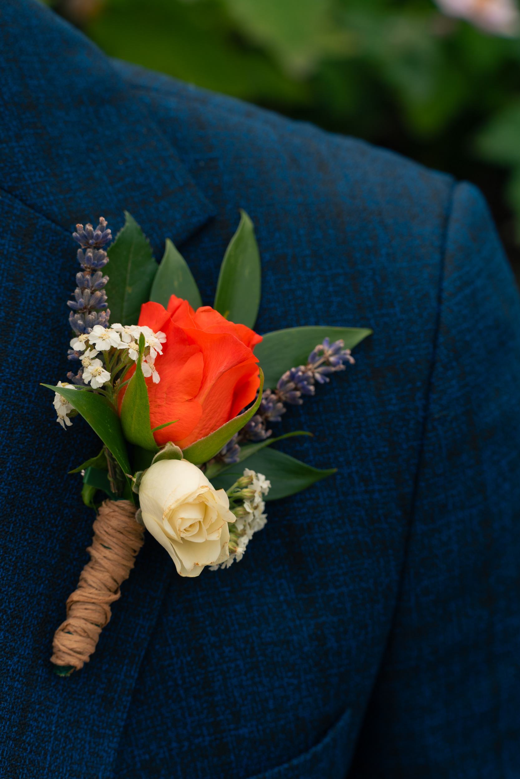 Aberdeen wedding photography: Detail shot of orange and cream buttonhole against blue suit.