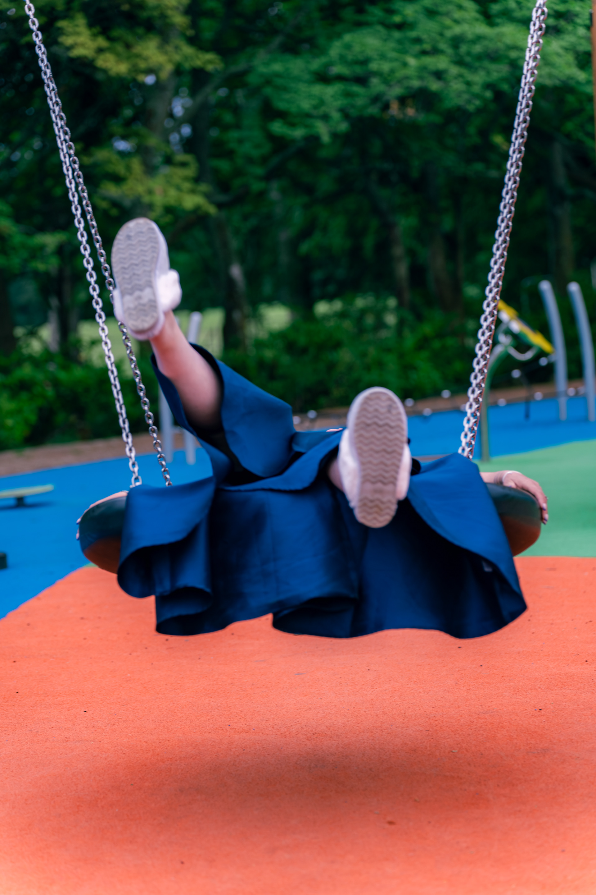 We see slippered feet emerging from a dark blue formal dress as a wedding guest lies across the tyre swing in Hazlehead Park
