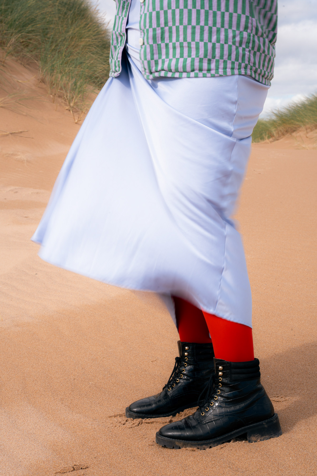 The wind catches a lilac skirt and it becomes a blur of movement around legs in bright red tights and big black boots. They are standing on an Aberdeenshire beach.