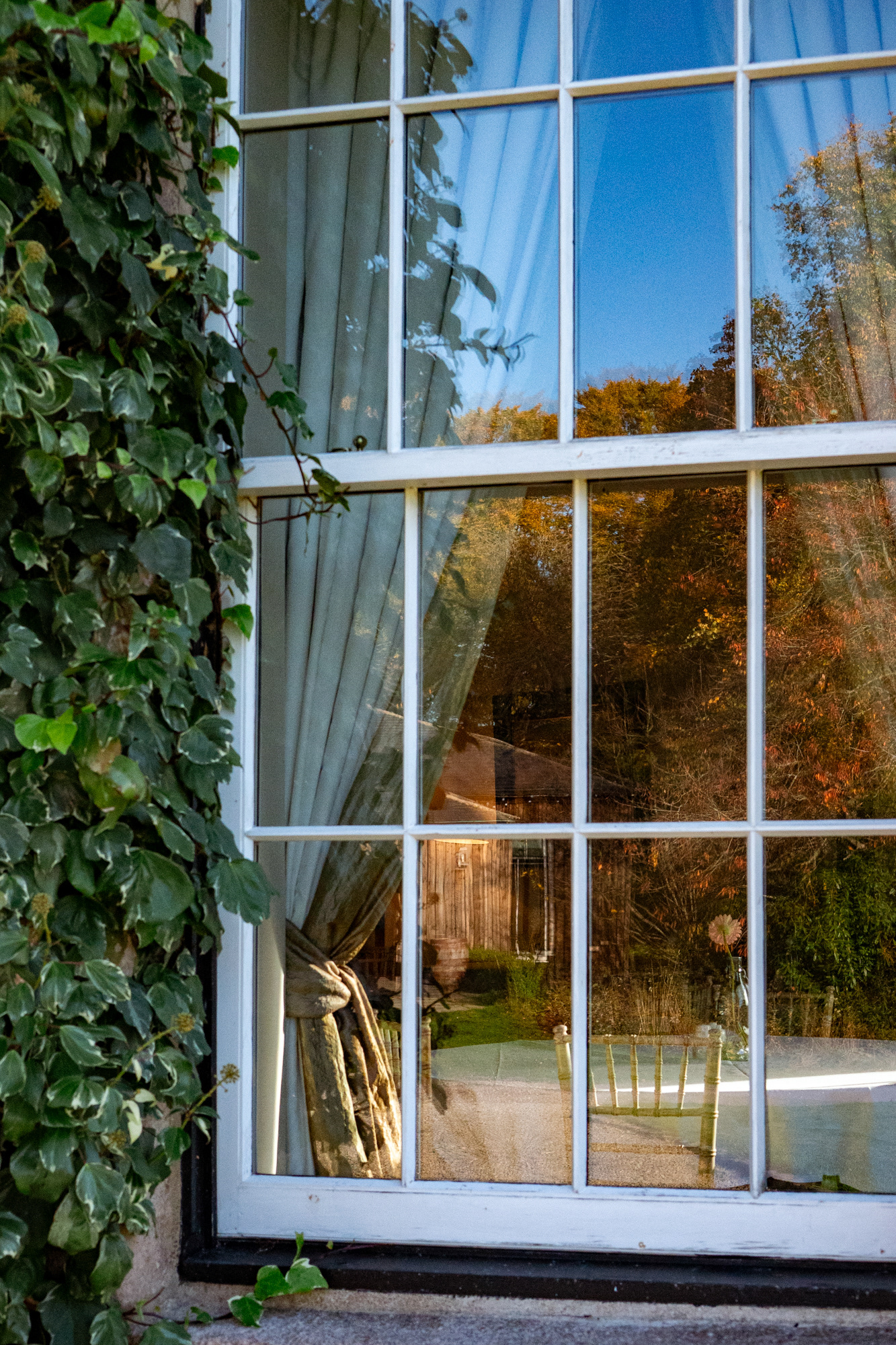 Logie Country House: A formal dining room seen through a window, with autumn trees reflected on the glass