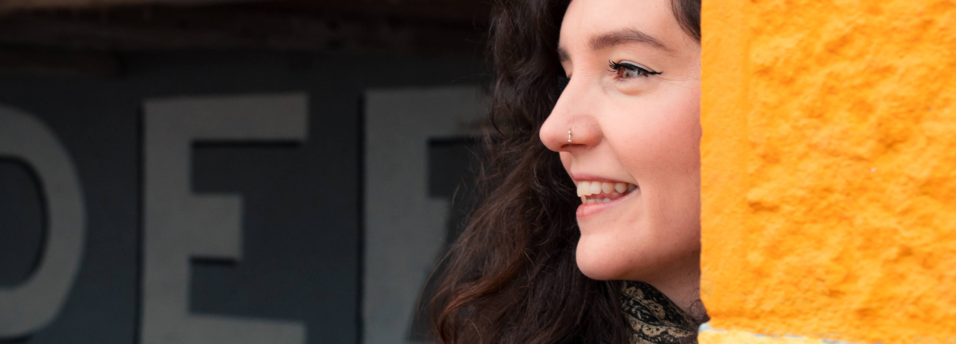 A close up of young woman with a a nose ring smiling off to the side, taken during an Aberdeen main character photo shoot