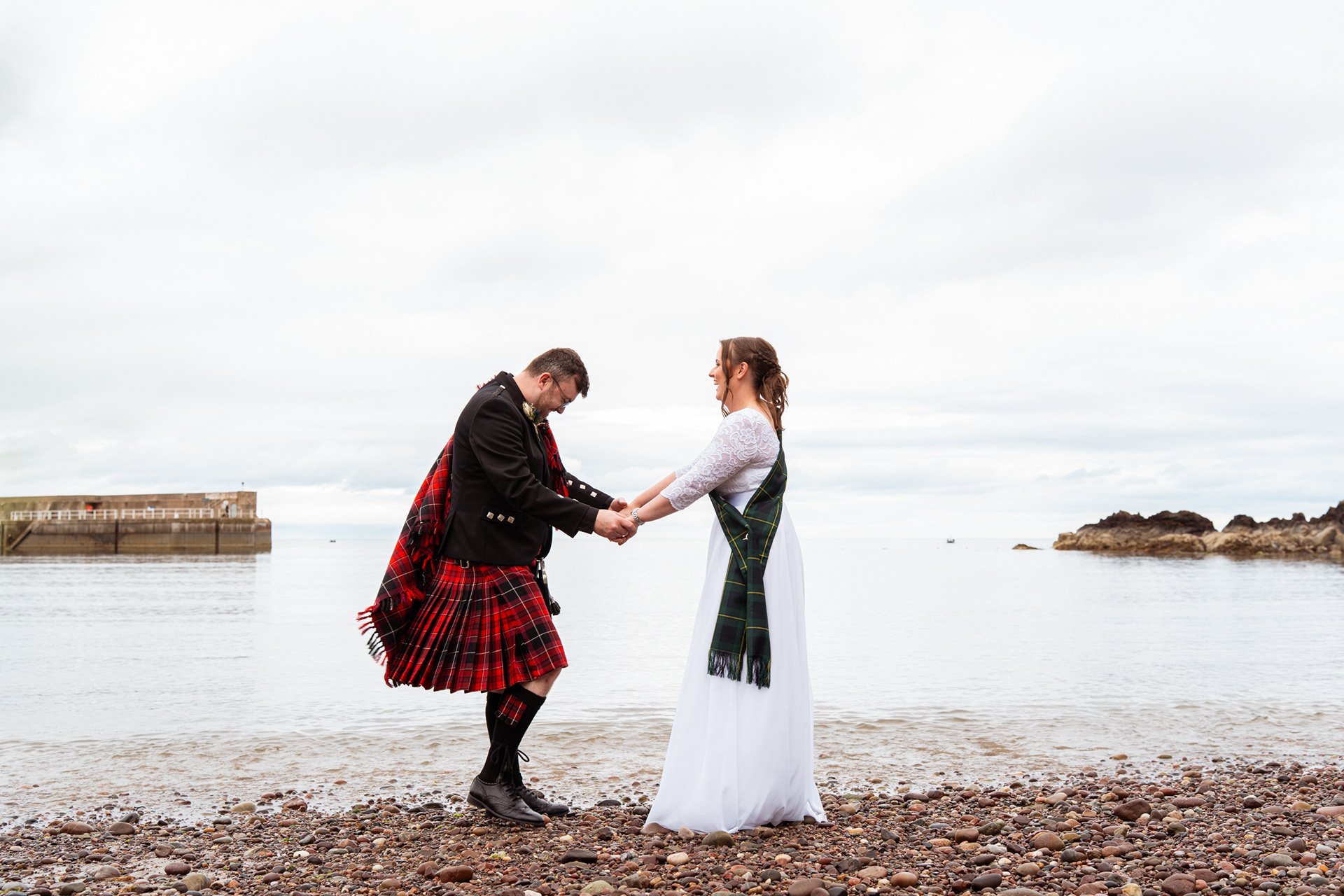 Stonehaven wedding: Bride and groom are pictured with the sea shining behind them.