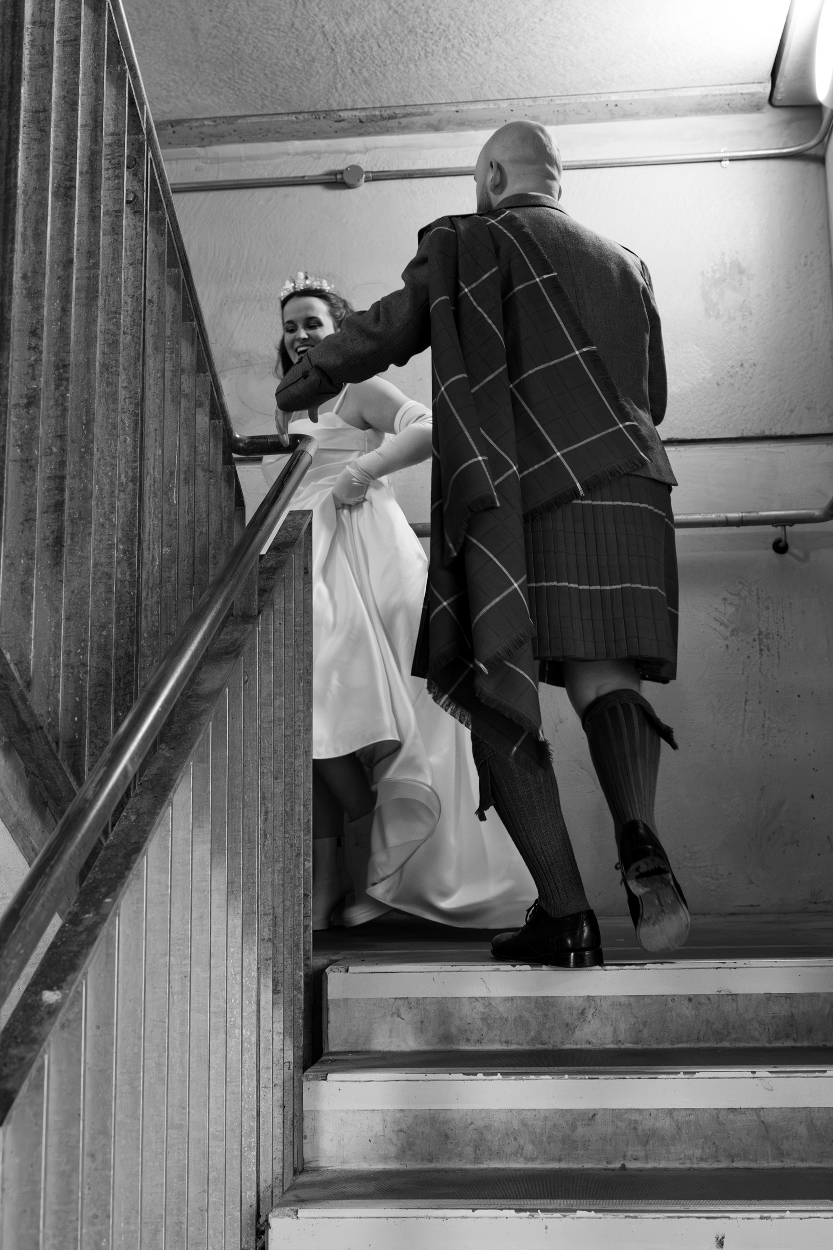 Alternative Aberdeen Wedding Photography: Newlyweds laugh walking up the stairs in a car park.