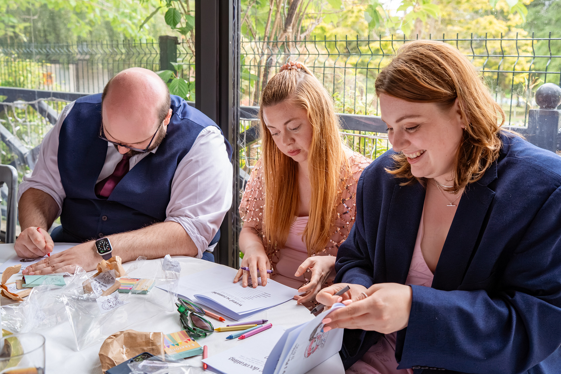 Two women and a man are very focused on the workbooks in front of them.
