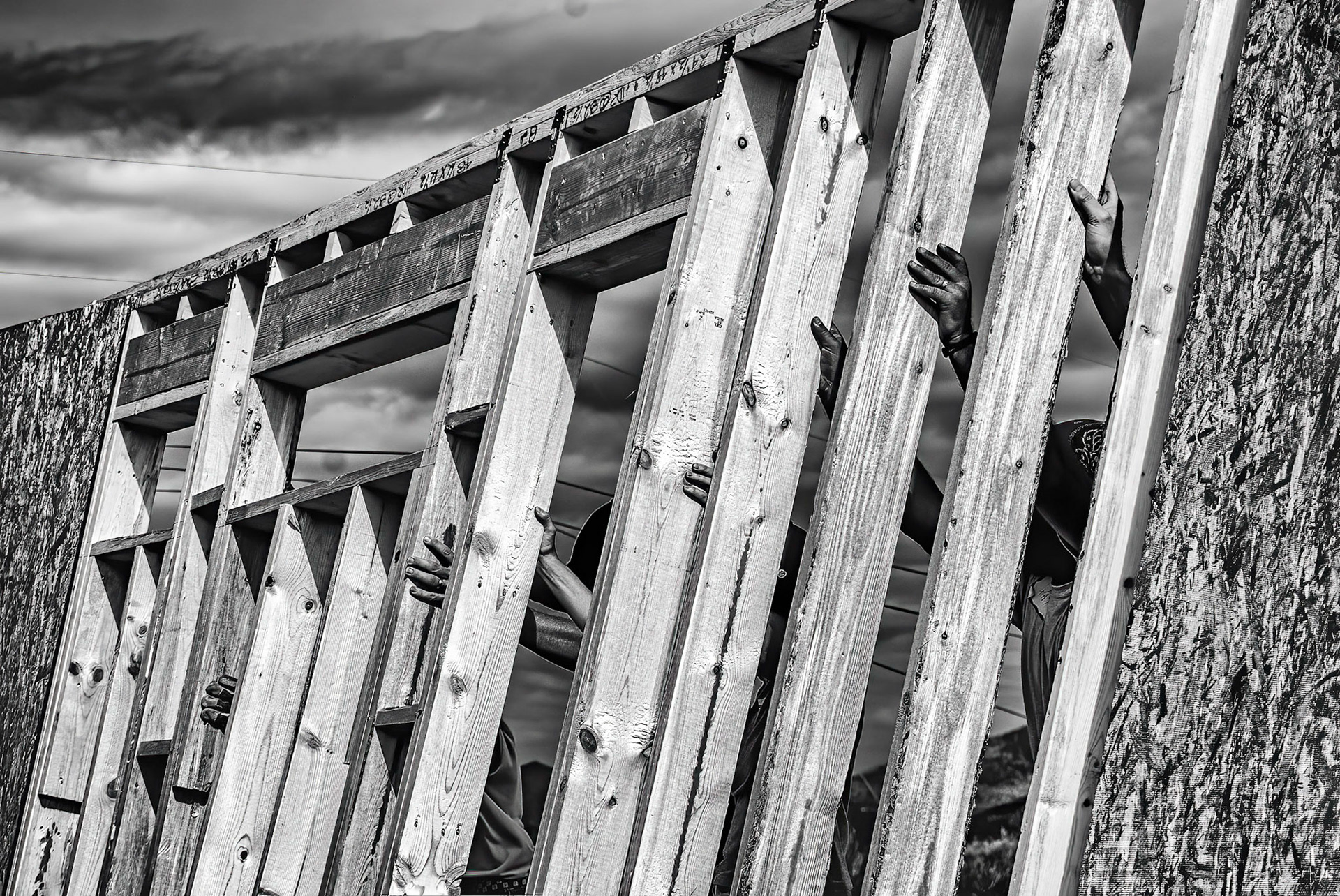 Hands of volunteers raising a wall for Habitat for Humanity home